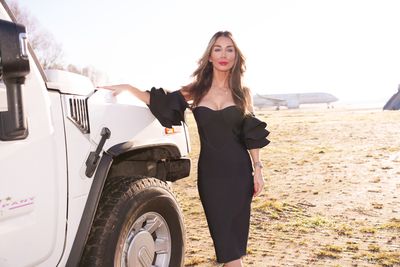 Private jet fashion shoot organised by Marsha Bagmeijer, model in a black ruffle-sleeve dress beside a white Hummer on the airfield, private jets in the distance